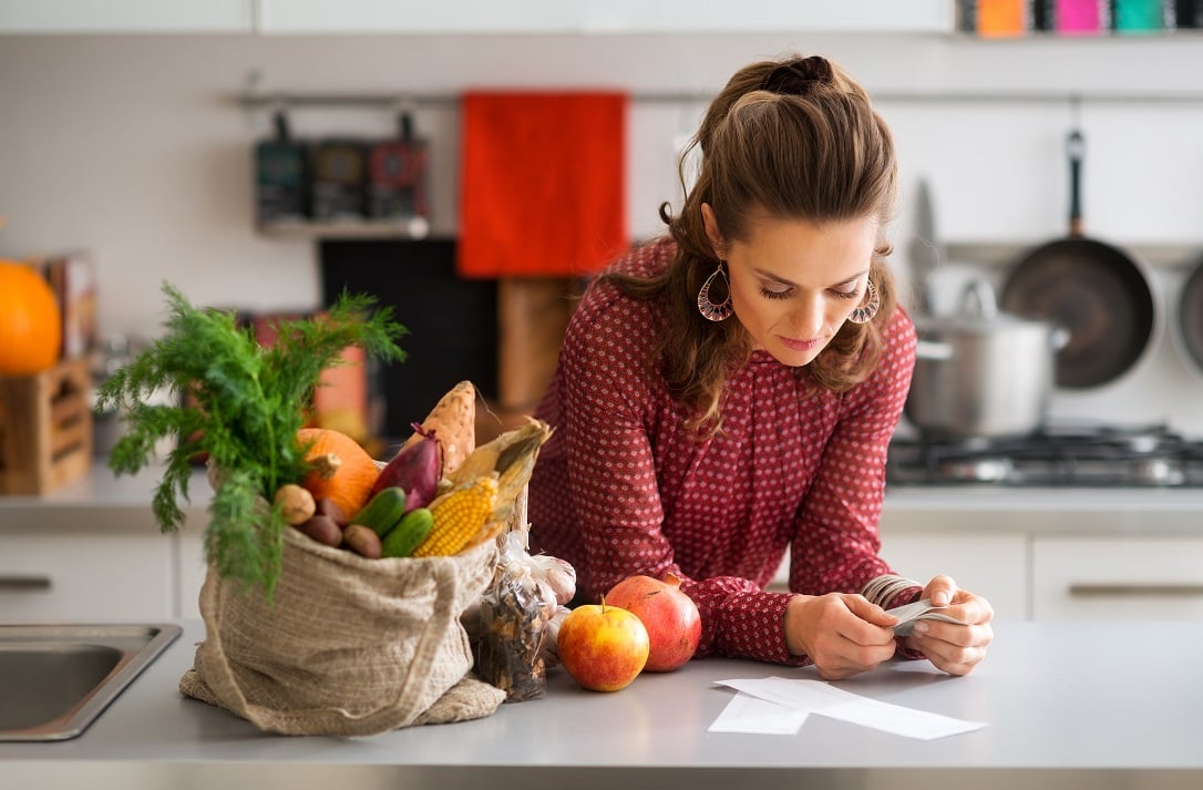 Woman with groceries looking at receipt